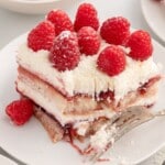 Recipe card image for Raspberry Tiramisu featuring a plated slice of the layered dessert topped with fresh raspberries and white chocolate. The image showcases creamy mascarpone filling, raspberry preserves, and ladyfinger cookies with the finished dessert presented as a serving suggestion.