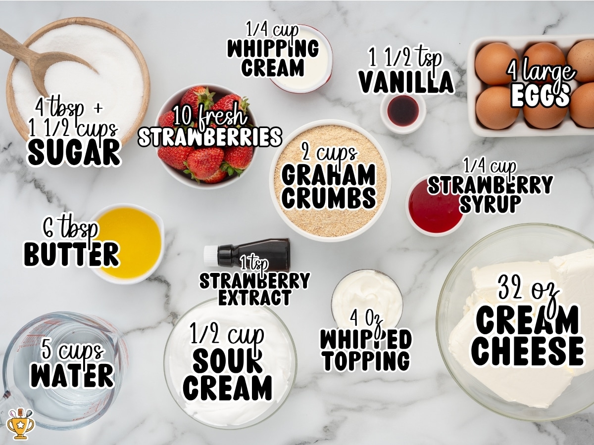 Overhead photo of ingredients for Strawberries and Cream Cheesecake on a marble background, including sugar, fresh strawberries, whipping cream, vanilla, eggs, graham cracker crumbs, strawberry syrup, butter, strawberry extract, sour cream, whipped topping, cream cheese, and water with ingredient labels and measurements.
