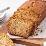 Sliced homemade Banana Bread loaf on a wooden cutting board, showcasing its moist, tender crumb and golden brown crust, perfect for breakfast, snacking, or dessert.