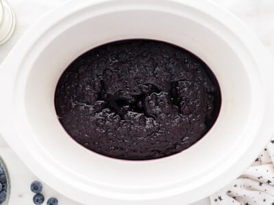 Thick Blueberry Butter reducing in a slow cooker after blending, showing the deep purple fruit mixture cooked down to a rich, glossy, spreadable consistency before transferring to jars.