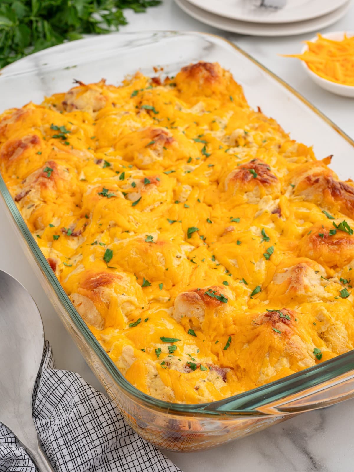 Freshly baked Chicken Bubble Biscuit Bake in a glass casserole dish with golden biscuit pieces, melted cheddar cheese, creamy chicken filling, and chopped parsley.