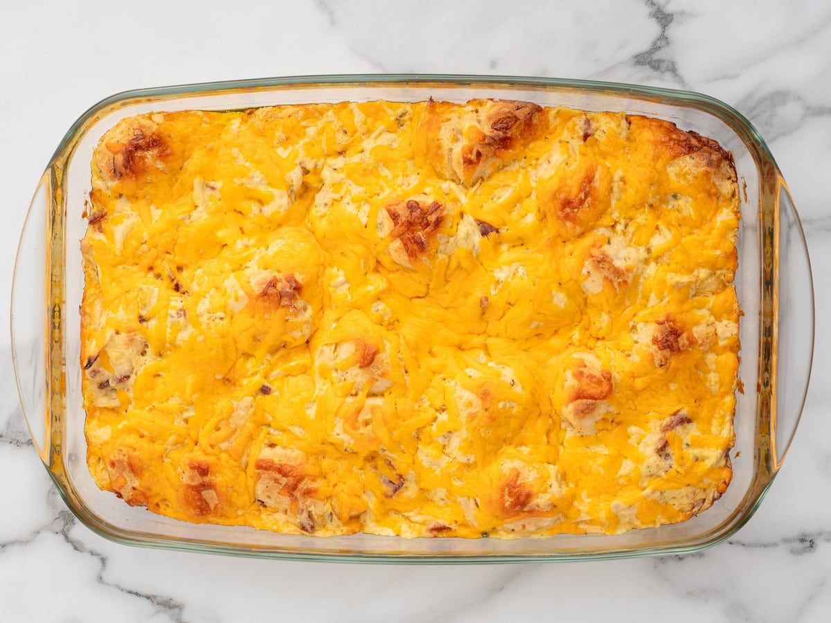 Overhead view of freshly baked Chicken Bubble Biscuit Bake in a glass casserole dish with golden biscuit pieces and melted cheddar cheese.