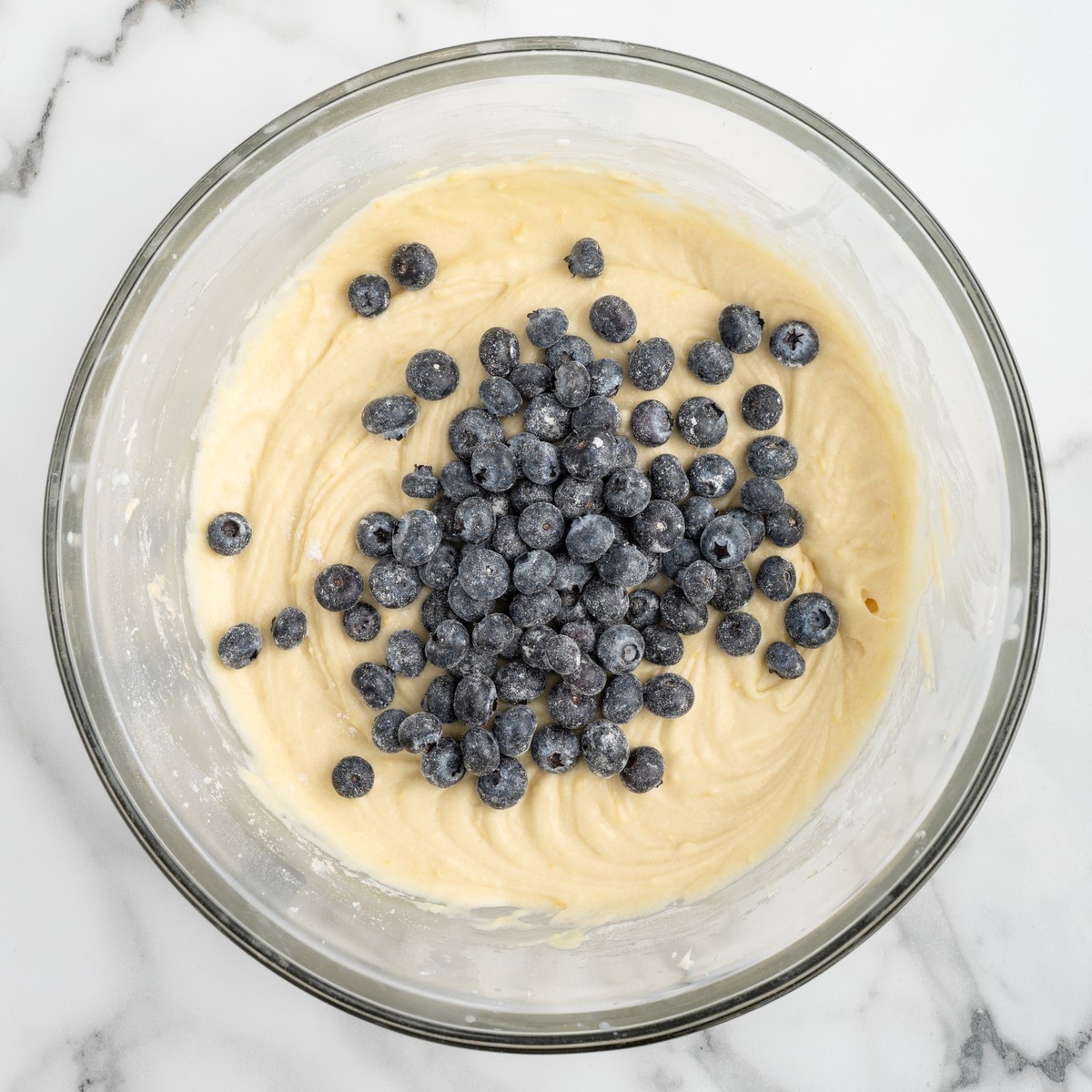 Smooth, creamy Lemon Blueberry Pound Cake batter mixed until light and fluffy in a glass bowl before fresh blueberries are folded in.