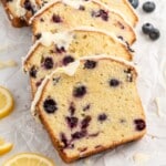 Sliced Lemon Blueberry Pound Cake topped with a thick homemade lemon glaze, showing a buttery crumb packed with juicy blueberries and fresh lemon slices for garnish.