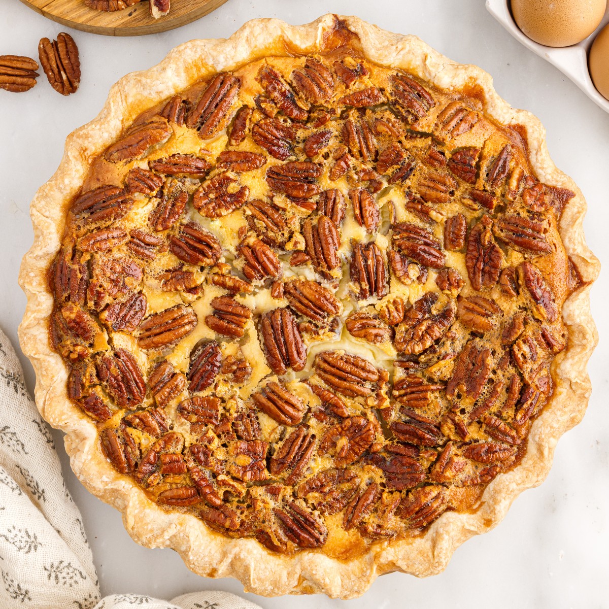 Overhead view of a freshly baked Pecan Cheesecake Pie with a golden flaky crust and a generous topping of whole and chopped pecans.