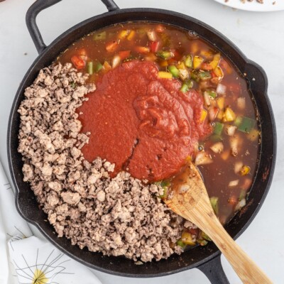 Cooked ground beef and Italian sausage returned to the skillet with crushed tomatoes, beef broth, and sautéed peppers to make Stuffed Pepper Casserole.