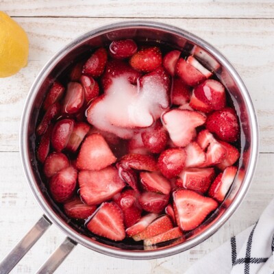 Fresh strawberries, sugar, and water combined in a saucepan before cooking to make homemade strawberry syrup for Strawberry Lemonade.