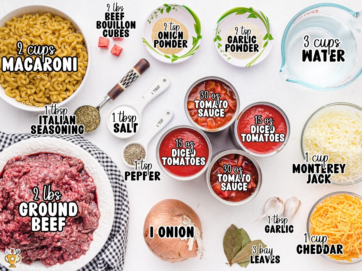 American Chop Suey ingredient layout labeled with 2 cups macaroni, 2 pounds ground beef, 2 beef bouillon cubes, 2 teaspoons onion powder, 2 teaspoons garlic powder, 3 cups water, 1 tablespoon Italian seasoning, 1 tablespoon salt, 1 teaspoon pepper, 30 ounces tomato sauce, 15 ounces diced tomatoes, 1 onion, 1 tablespoon garlic, 3 bay leaves, 1 cup Monterey Jack cheese, and 1 cup cheddar cheese.