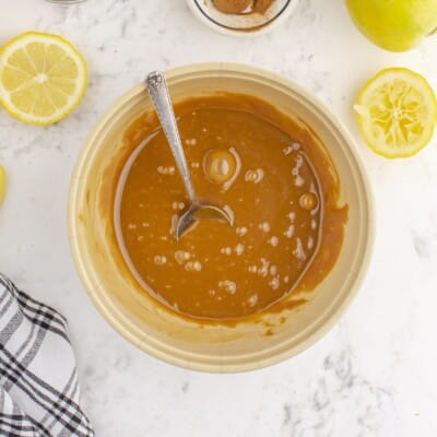 Overhead view of smooth homemade caramel sauce in a bowl with a spoon, prepared for drizzling over the Caramel Apple Crumb Pie filling.