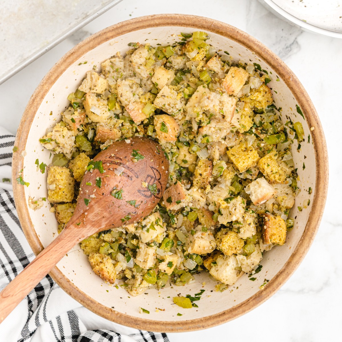 Cornbread Stuffing mixture tossed together in a large bowl with bread cubes, cornbread, celery, onion, parsley, sage, and seasonings.