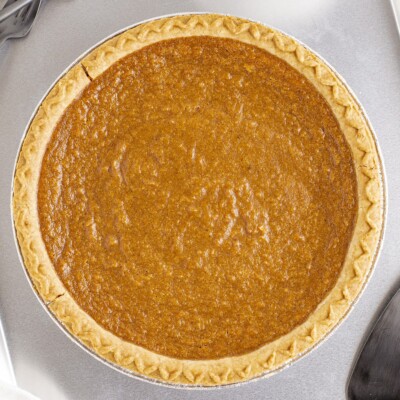 Overhead view of a fully baked Sweet Potato Pie with golden-brown filling and a crimped crust in a disposable pie pan.